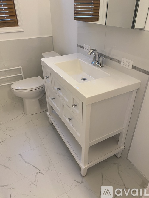 A white bathroom with a sink, toilet and a mirror.