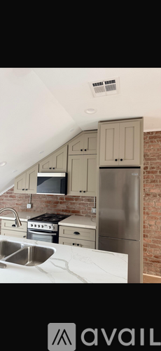 A kitchen with a brick wall and a stainless steel refrigerator.