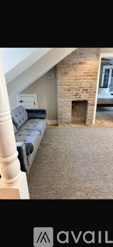 A room with a grey sofa and a fireplace.