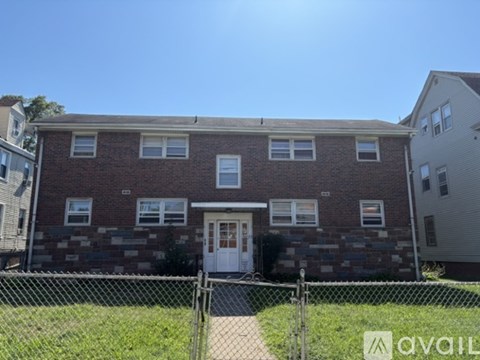 A brick house with a white door and windows is for sale.