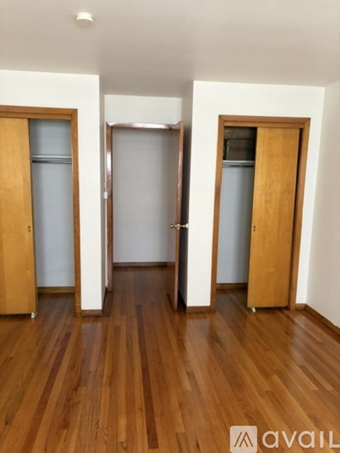 A room with wooden floors and three doors.