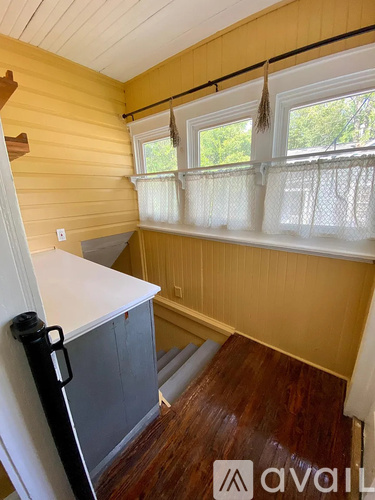 A room with wooden walls and a window with white curtains.