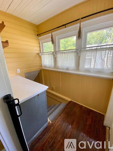 A room with wooden walls and a window with white curtains.