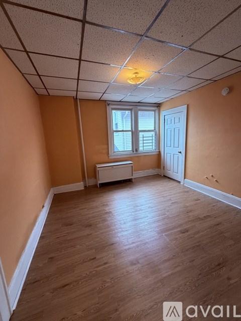 A room with wooden flooring and a window with blinds.