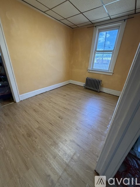 A room with wooden flooring and a window.