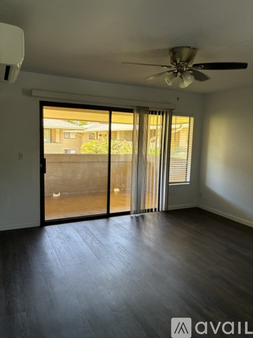 A room with a ceiling fan and sliding glass doors leading to a balcony.