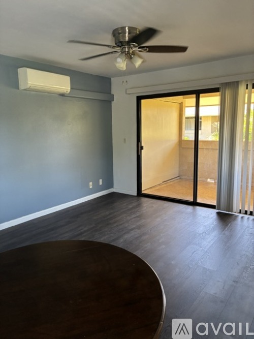 A room with a ceiling fan and sliding glass doors.