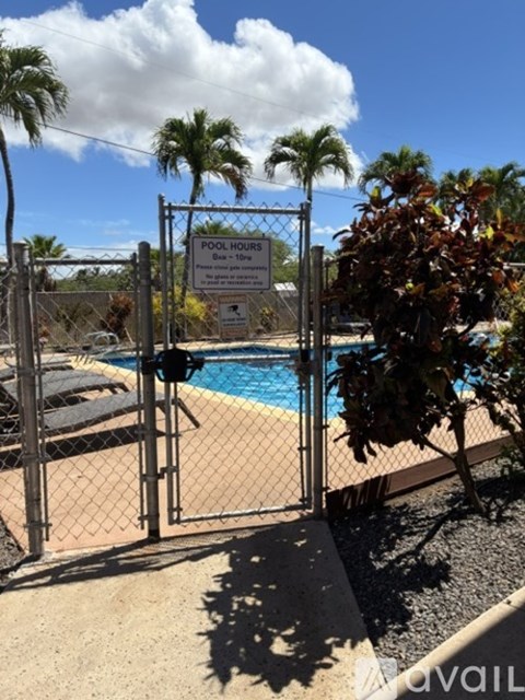 A pool surrounded by a fence with a sign that says pool hours.