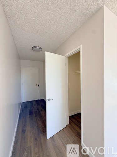 A hallway with a white door and a wooden floor.