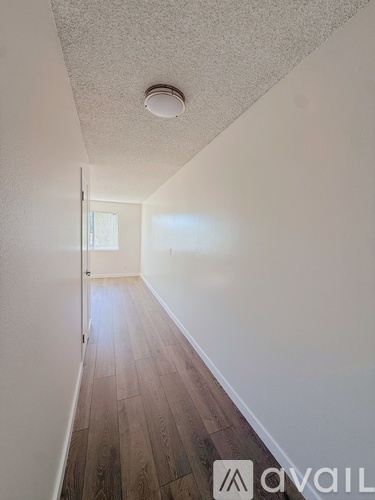 A long hallway with wood floors and white walls.