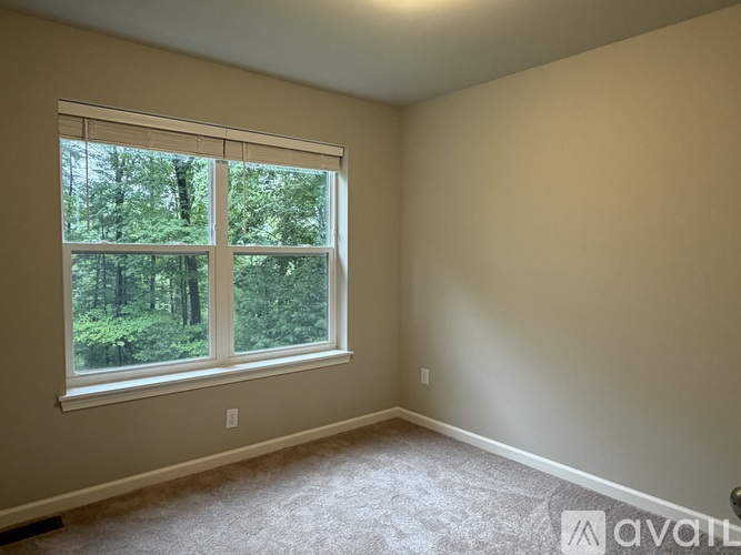A room with a large window overlooking a forest.