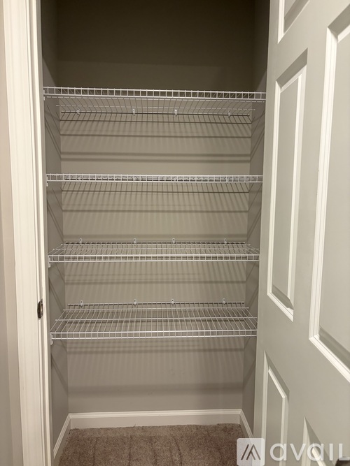 Empty wire shelving in a white closet.