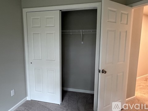 A white closet door is open revealing a grey interior.