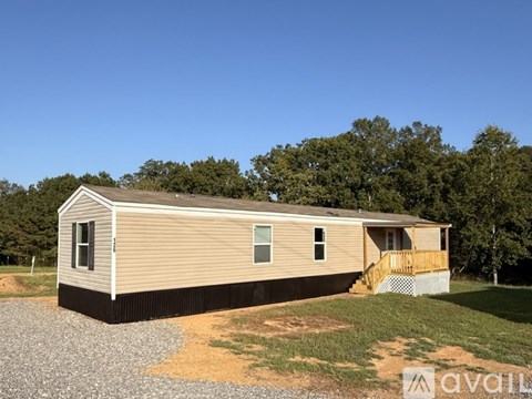 A mobile home with a gravel driveway in front.