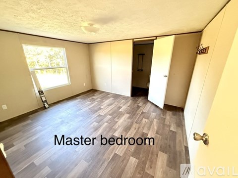 A master bedroom with wood flooring and a window.