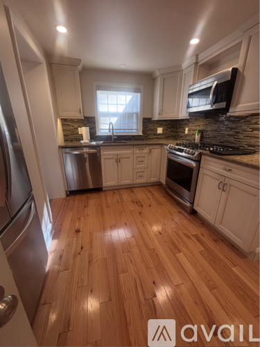 A kitchen with wooden floors and stainless steel appliances.