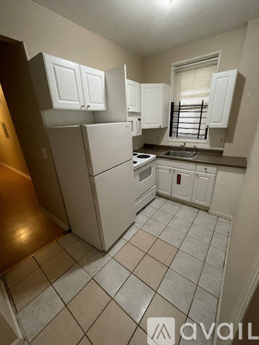 A kitchen with white cabinets and a white refrigerator.