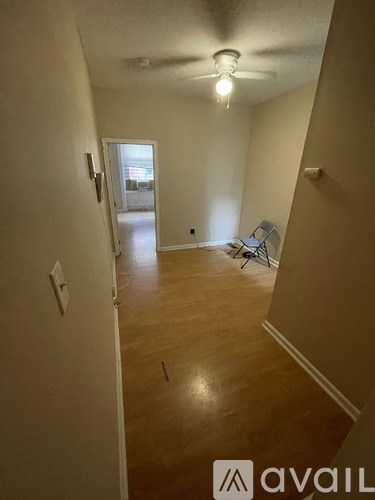 A room with a ceiling fan and a chair in it.