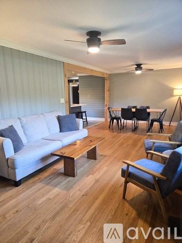 A living room with a white couch, wooden coffee table, and a dining table with chairs.