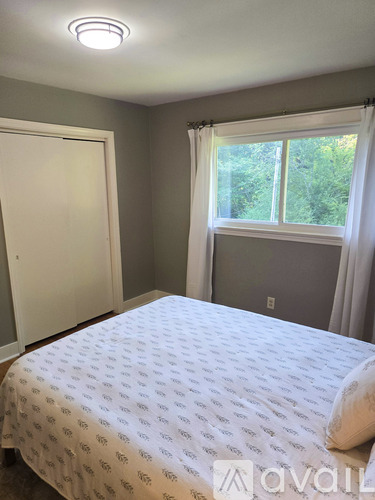 A bedroom with a bed, window, and a closed door.
