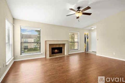 A spacious living room with a fireplace and a ceiling fan.