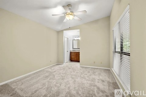 A spacious room with a carpeted floor and a ceiling fan.