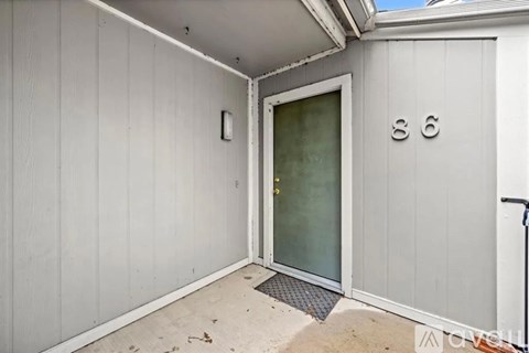 A white wooden building with a glass door and a number 86 on the wall.