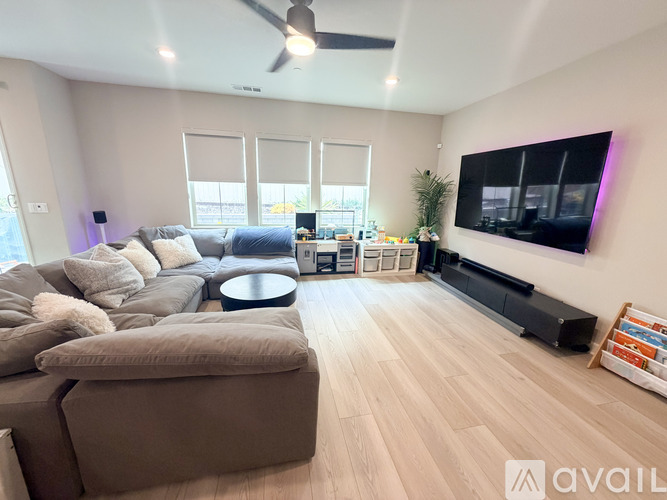 A living room with a large couch and a flat screen TV mounted on the wall.