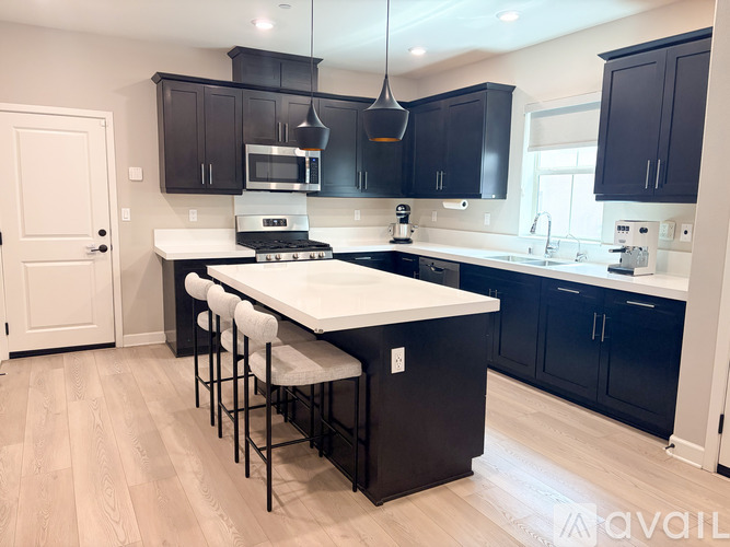 A kitchen with black cabinets and a white island.