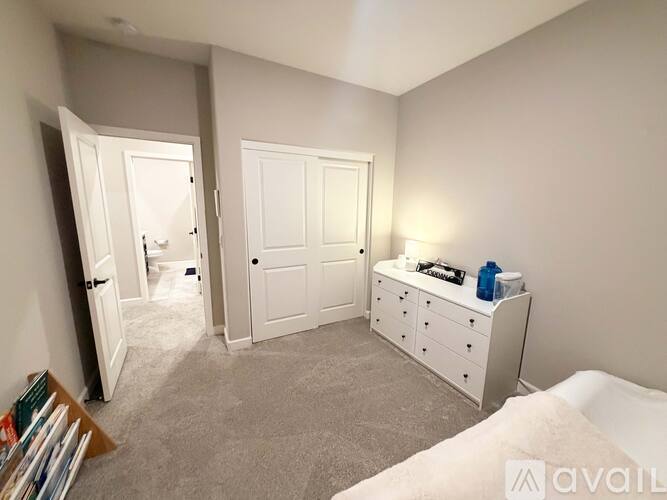 A bedroom with a white dresser and a bed in the corner.
