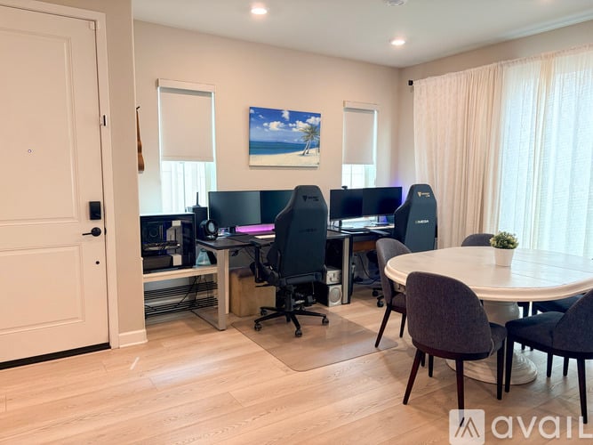 A room with a desk, chairs, and a painting on the wall.