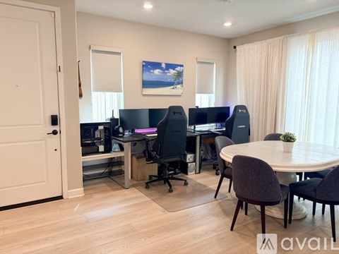 A room with a desk, chairs, and a painting on the wall.