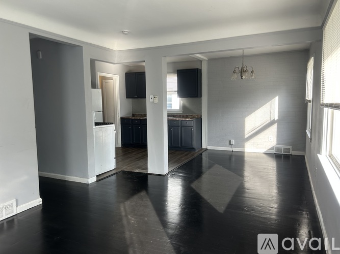 A spacious living room with a kitchen in the background.