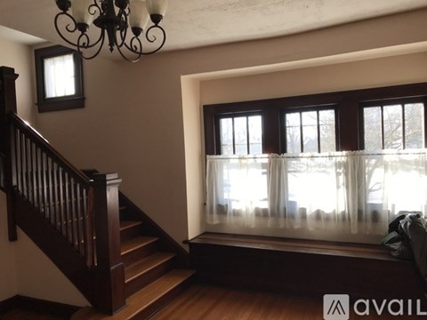 A room with a staircase and a window with curtains.
