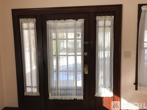 A brown door with white curtains and a gold handle.