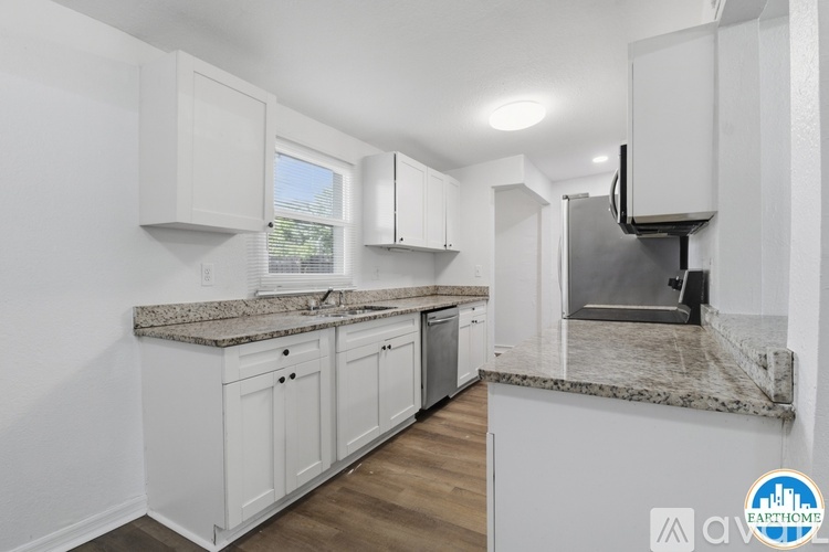 A kitchen with white cabinets and a granite countertop.
