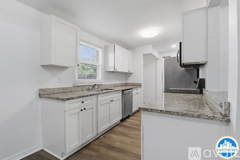 A kitchen with white cabinets and a granite countertop.