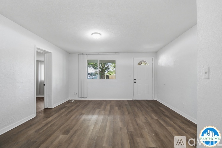 A spacious room with wooden floors and white walls.