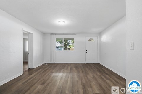A spacious room with wooden floors and white walls.