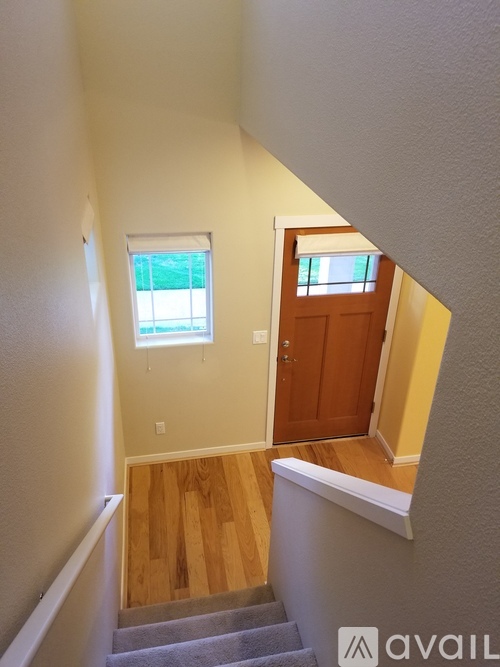 A stairway with a carpeted runner and wooden steps leading to a door.