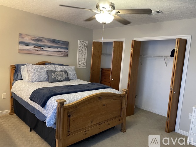 A bedroom with a bed, a ceiling fan, and a painting on the wall.
