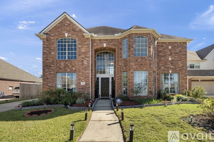 A large brick house with a front yard and a driveway.