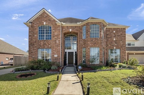 A large brick house with a front yard and a driveway.