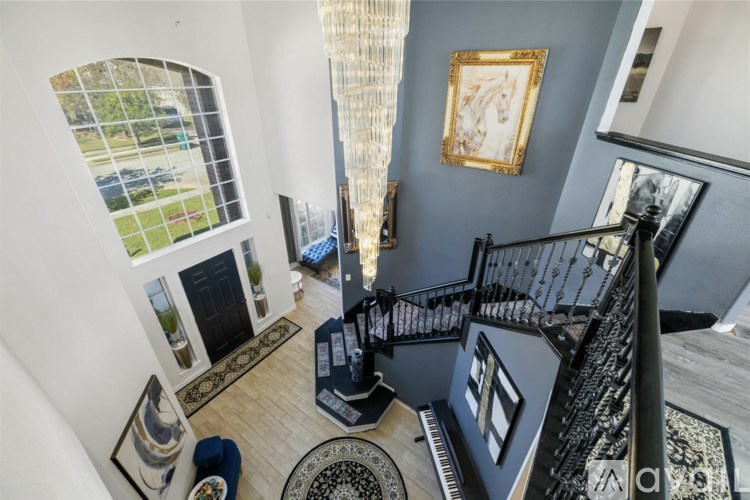 A staircase with a black railing and a piano at the bottom.