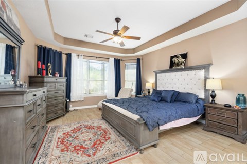 A bedroom with a large bed, a dresser, and a ceiling fan.