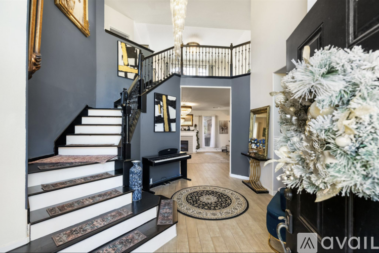 A Christmas tree is in a blue vase on a rug in front of a staircase.