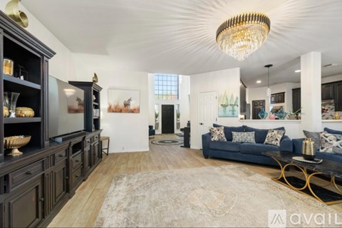 A living room with a blue couch and a chandelier.