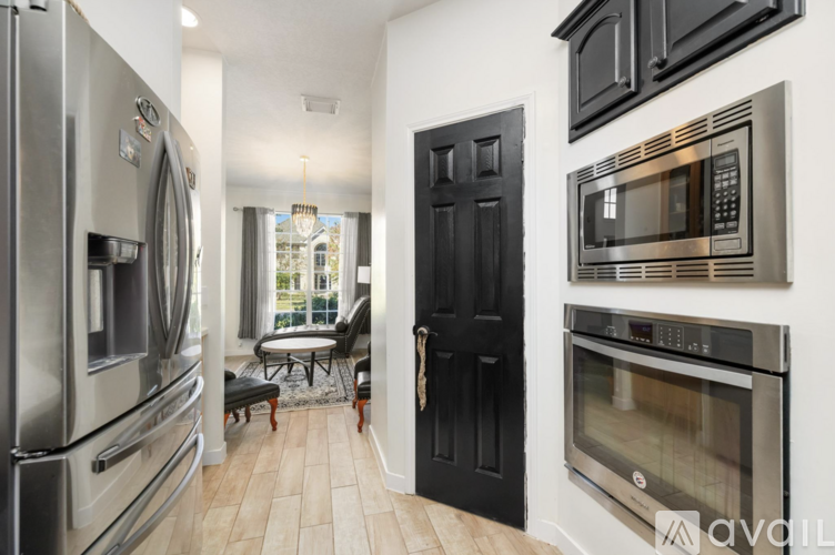 A kitchen with a black door and a stainless steel refrigerator.