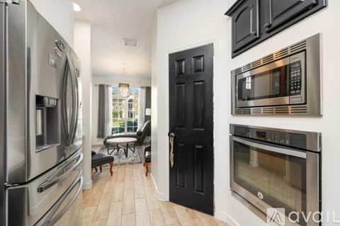 A kitchen with a black door and a stainless steel refrigerator.