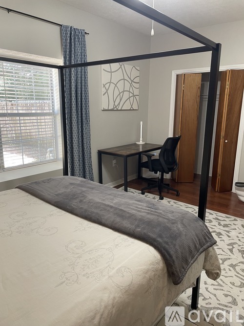 A bedroom with a four poster bed and a desk.